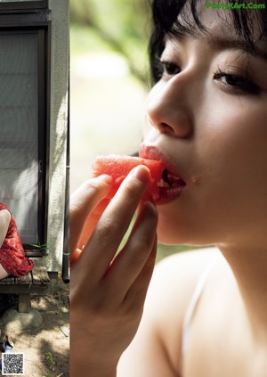 A woman in a red bathing suit sitting on a wooden bench.