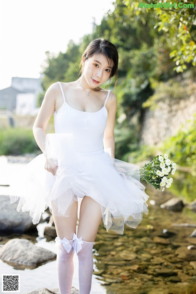 A woman in a white dress holding a bouquet of flowers.