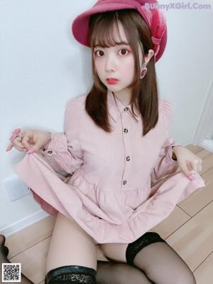 A woman in a pink shirt and black stockings posing for a picture.