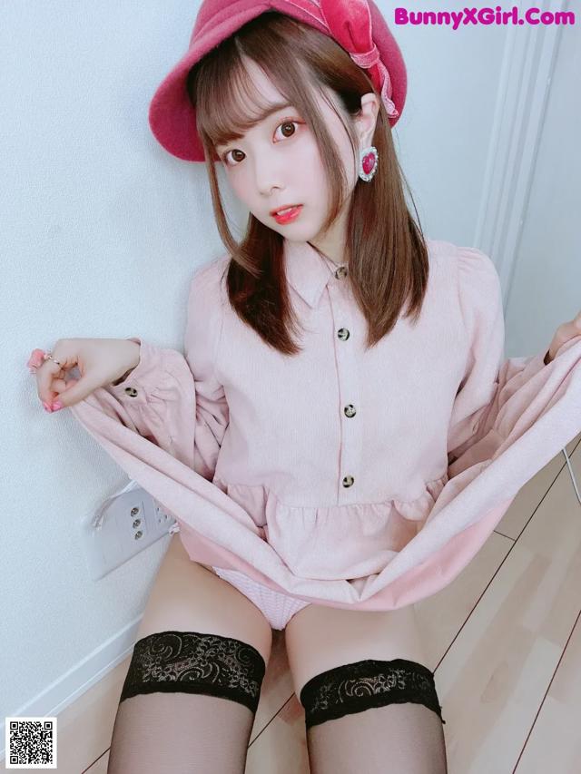 A woman in a pink shirt and black stockings posing for a picture.