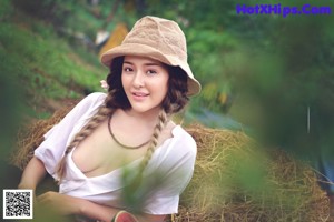 A woman in a straw hat sitting next to a basket of flowers.