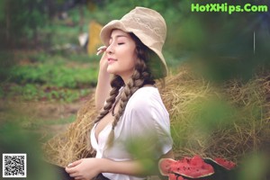 A woman sitting in a garden holding a watering can.