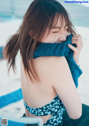 A woman in a blue and white floral swimsuit standing on the beach.