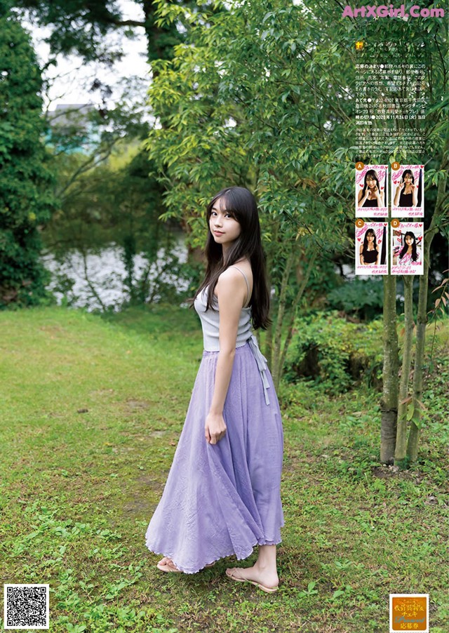 A woman in a long purple skirt standing in the grass.