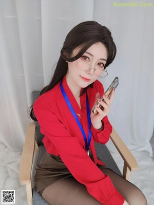 A woman in a red shirt and brown skirt posing on a white rug.