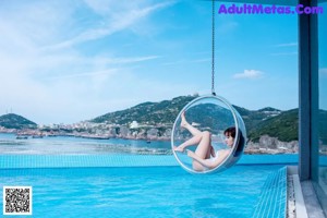 A woman in a white bathing suit standing next to a swimming pool.