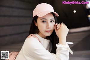 A woman wearing a pink hat sitting on the ground.