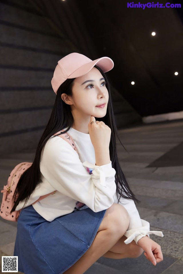 A woman wearing a pink hat sitting on the ground.