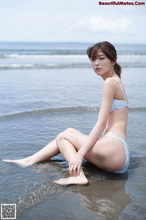 A woman in a white dress standing on a beach.