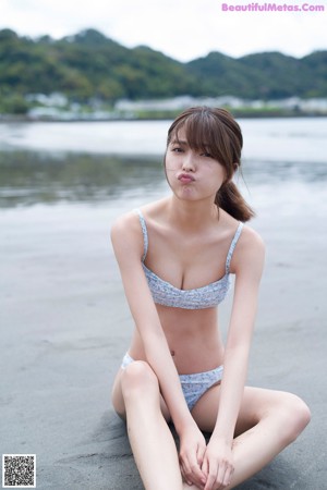 A woman in a blue and white bikini standing on a beach.