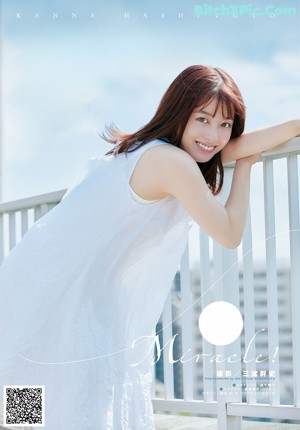 A woman with long brown hair and a white tank top.