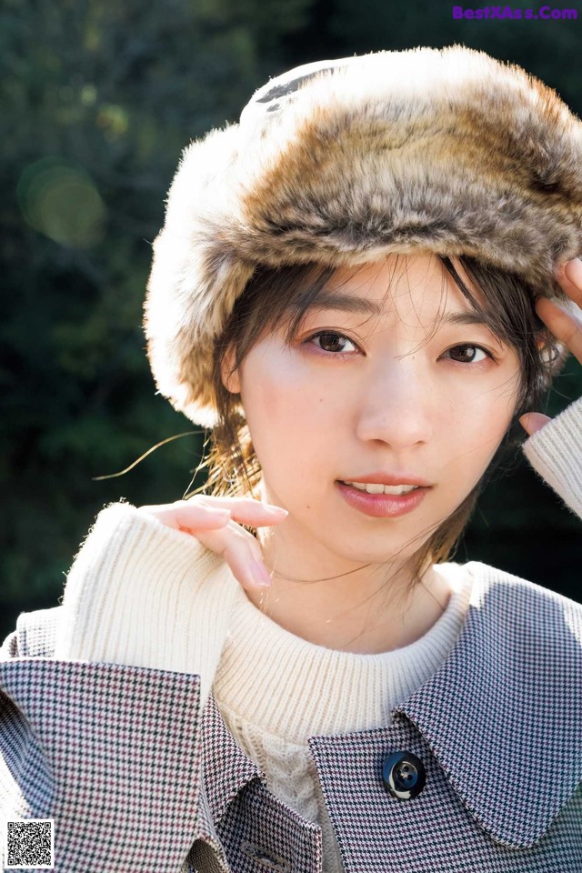 A woman wearing a fur hat is posing for a picture.