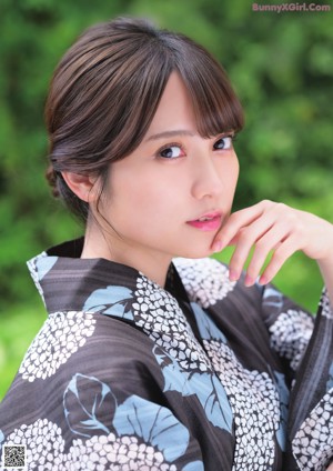 A young girl in a kimono sitting on a bed.