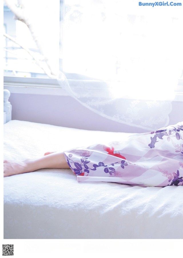 A woman laying on a bed in front of a window.