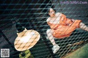 A woman in an orange jumpsuit standing next to a ladder.