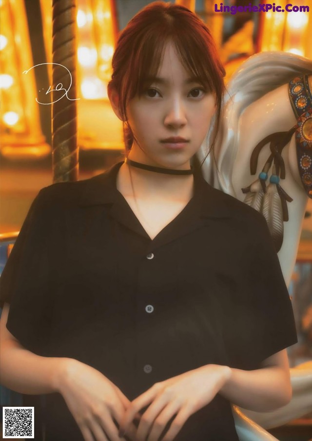 A woman in a black shirt standing next to a carousel.