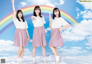 A group of three young women sitting on top of a wooden bench.