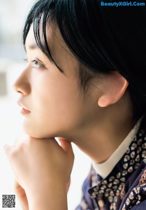 A woman in a blue kimono standing next to a body of water.