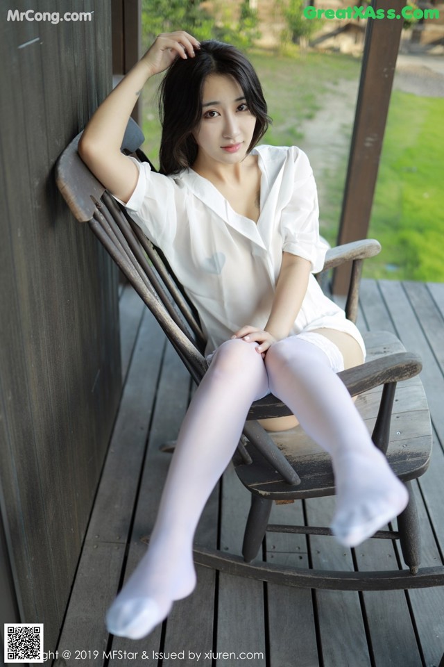 A woman sitting in a rocking chair on a porch.