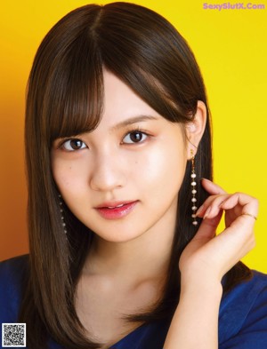 A woman with long brown hair and bangs is posing for a magazine.