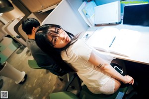 A woman sitting on a green chair in an office.